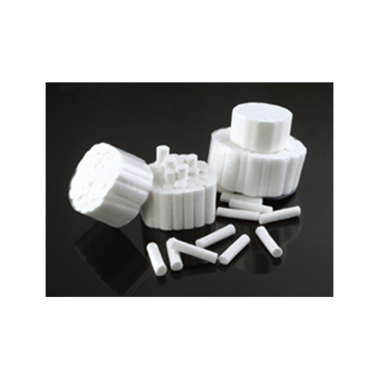 a bunch of white cotton rolls are stacked on top of each other on a black surface